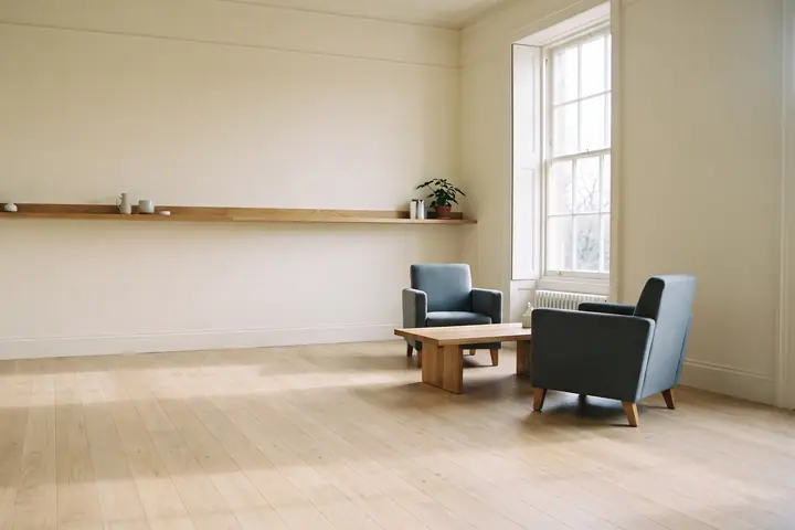 A quiet, light-filled room with two armchairs facing each other and a long low shelf.